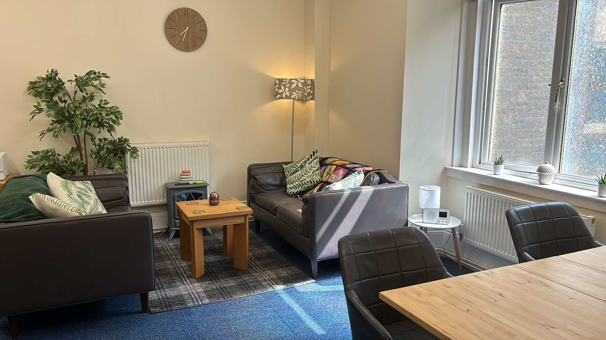 Bright room with large window, brown sofas and a table and chairs.