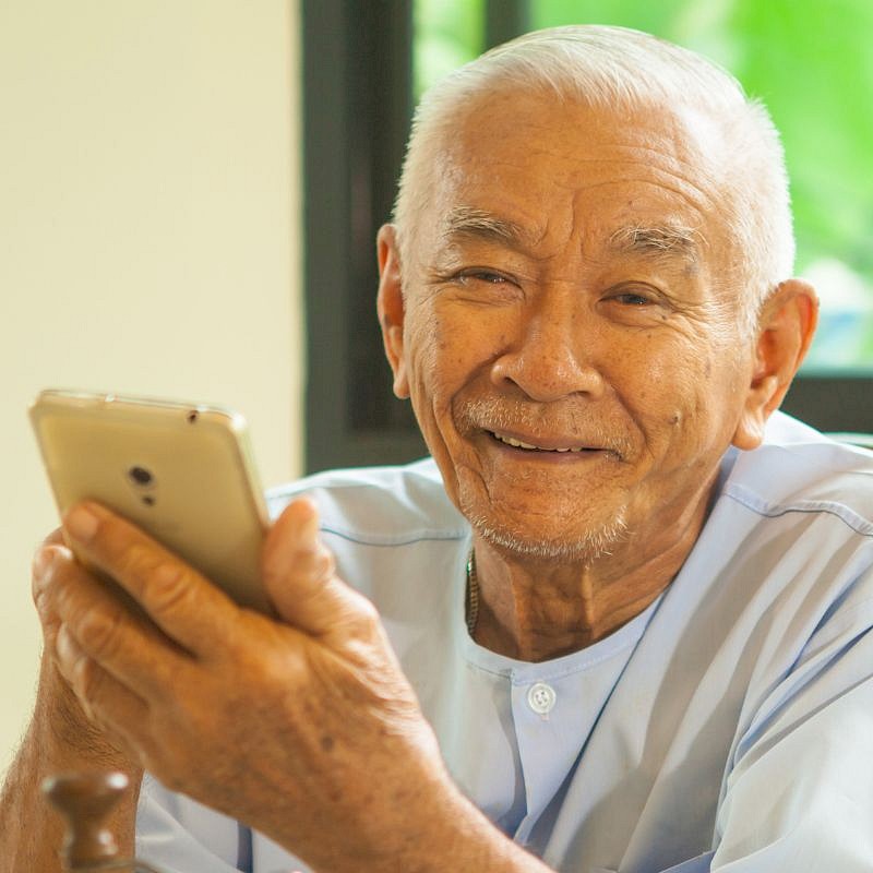 Older Man holding mobile phone in his hands and smiling