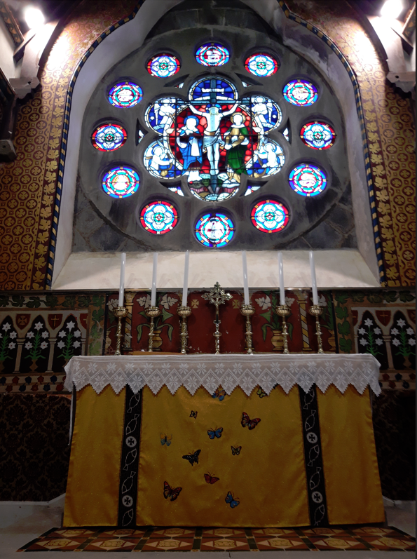 Stained glass window with 13 panels. Yellow alter with candles on it and hand painted flowers in the back ground. 