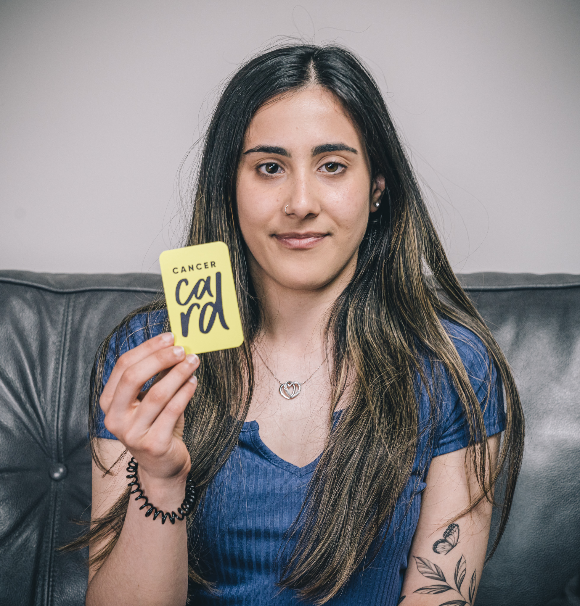 Young woman holding yellow cancer card with a QR code leading to our website and cancer support directory