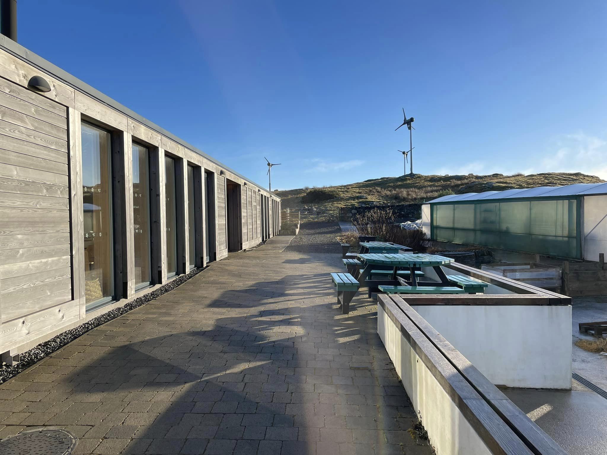 Large building with lots of glass windows, a walkway with an entrance to the garden.