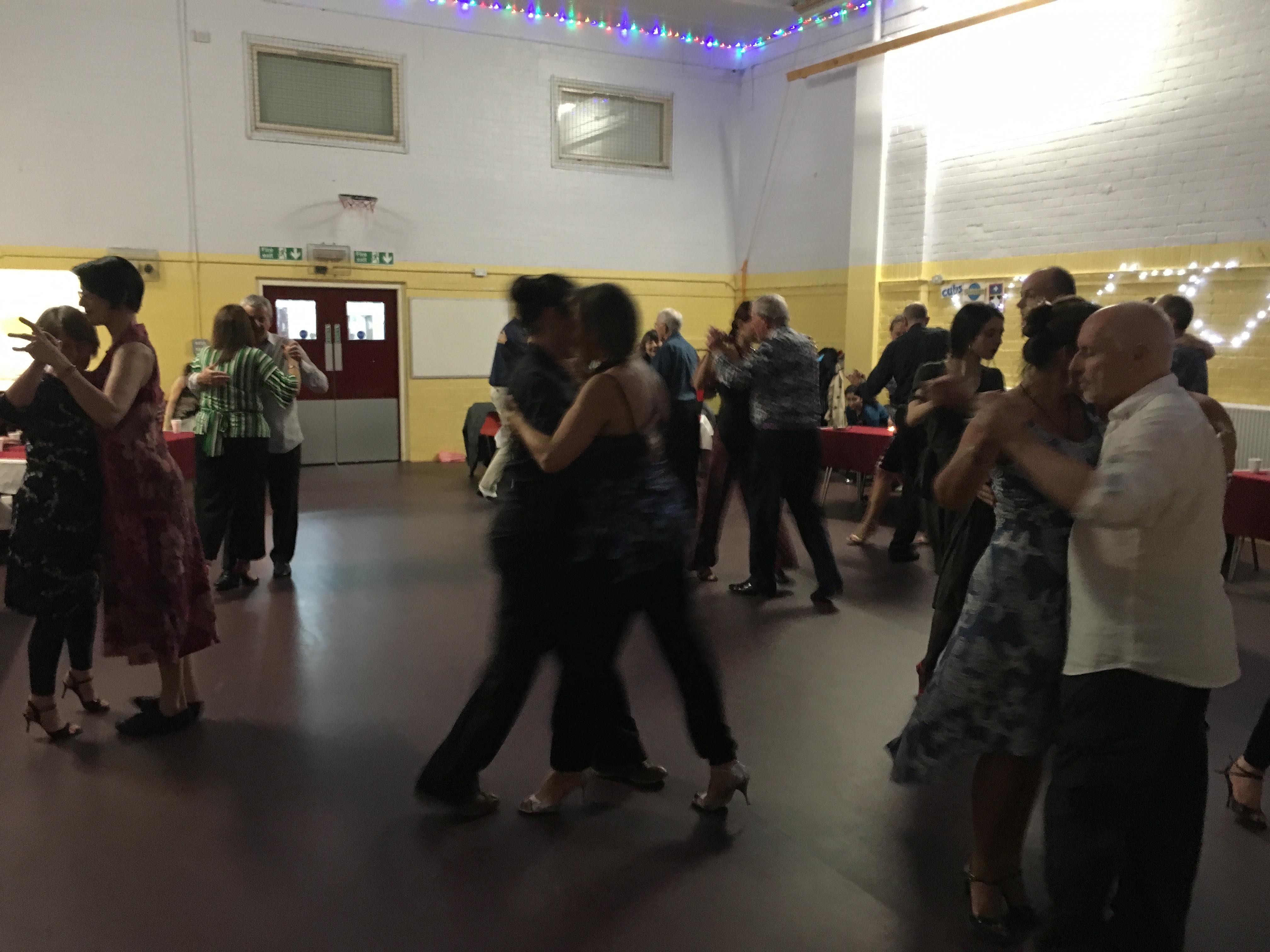 Group of people in a large room dancing the tango.