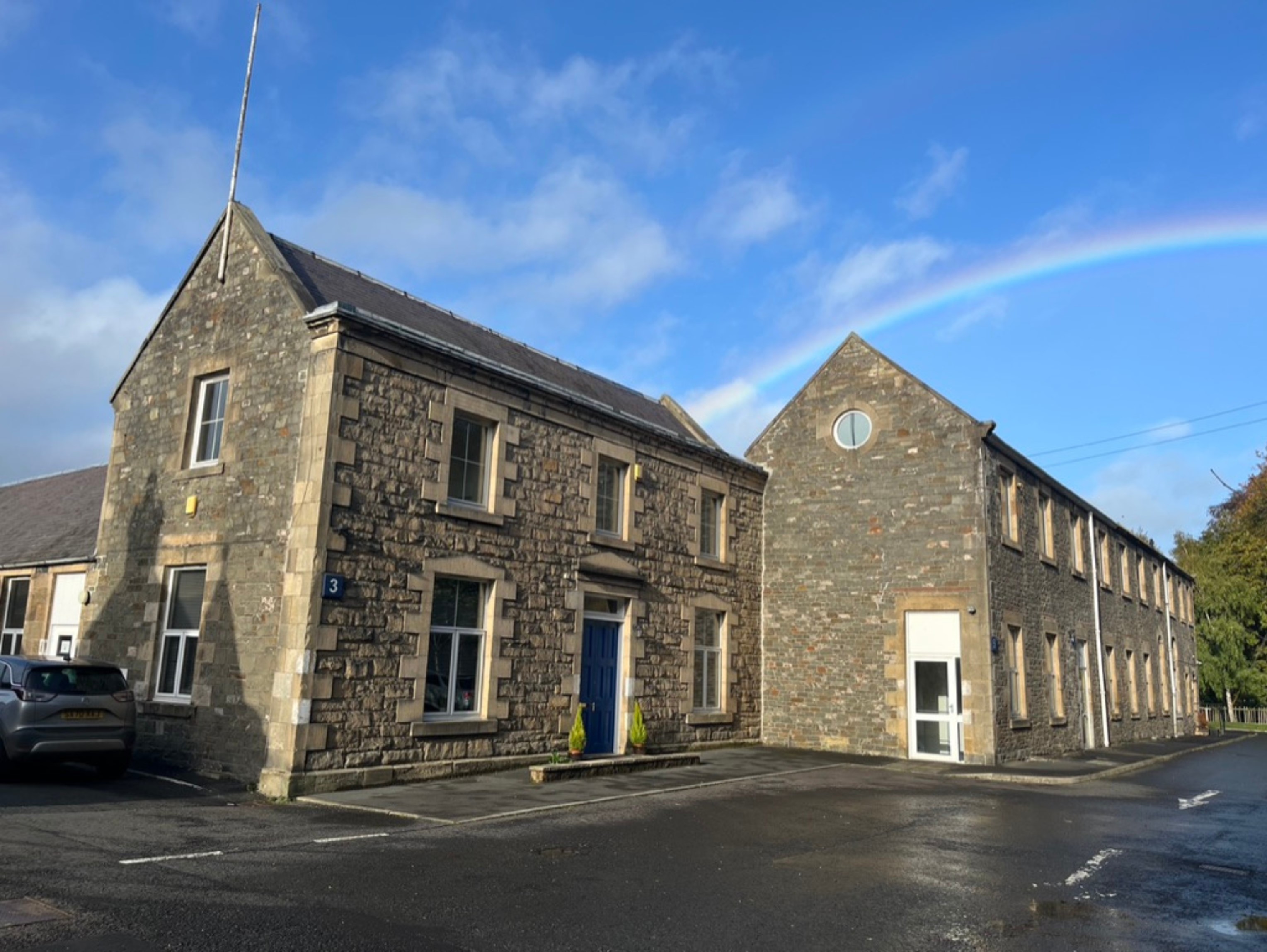 A side view of a large stone building with gable roof.