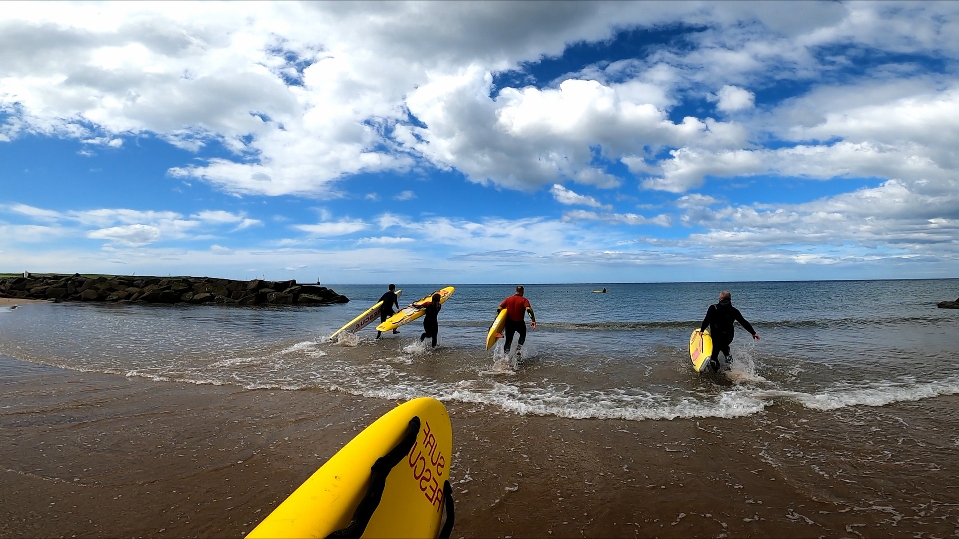 Four lifeguards entering the sea on rescue boards during a training session