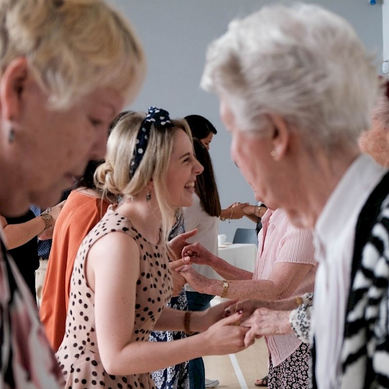 Two older women and a younger woman dancing in hall.