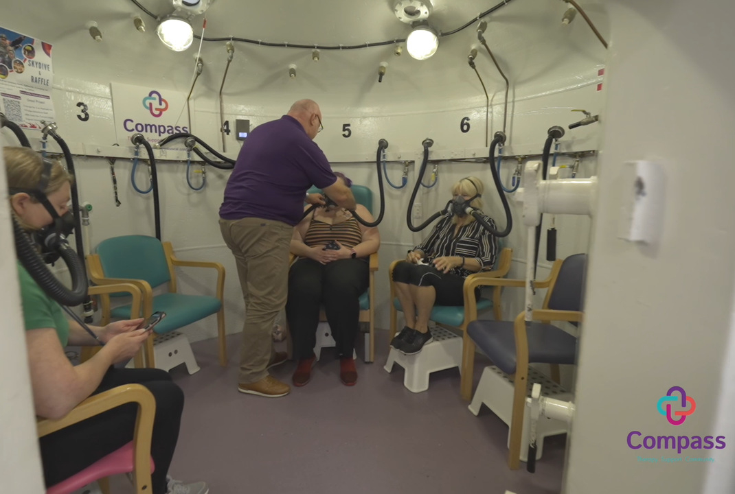 Circular room with seats around the perimiter. People sitting with oxygen masks over their faces.