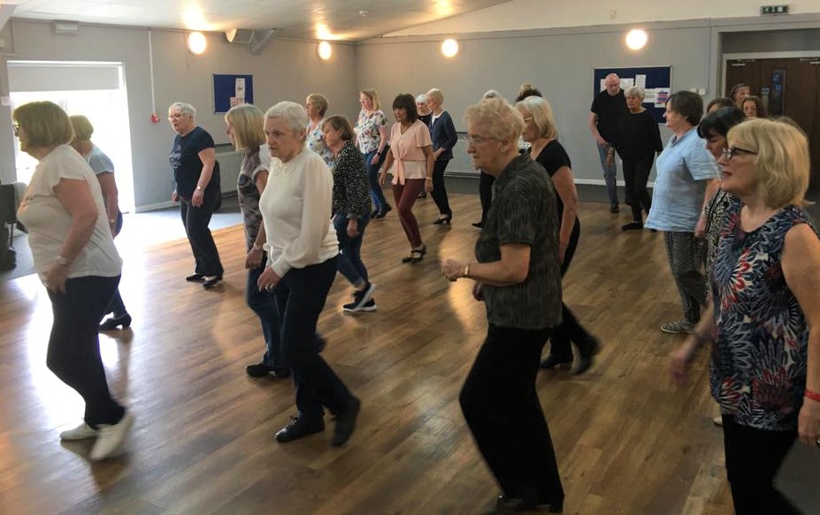 Ladies line dancing in a large hall