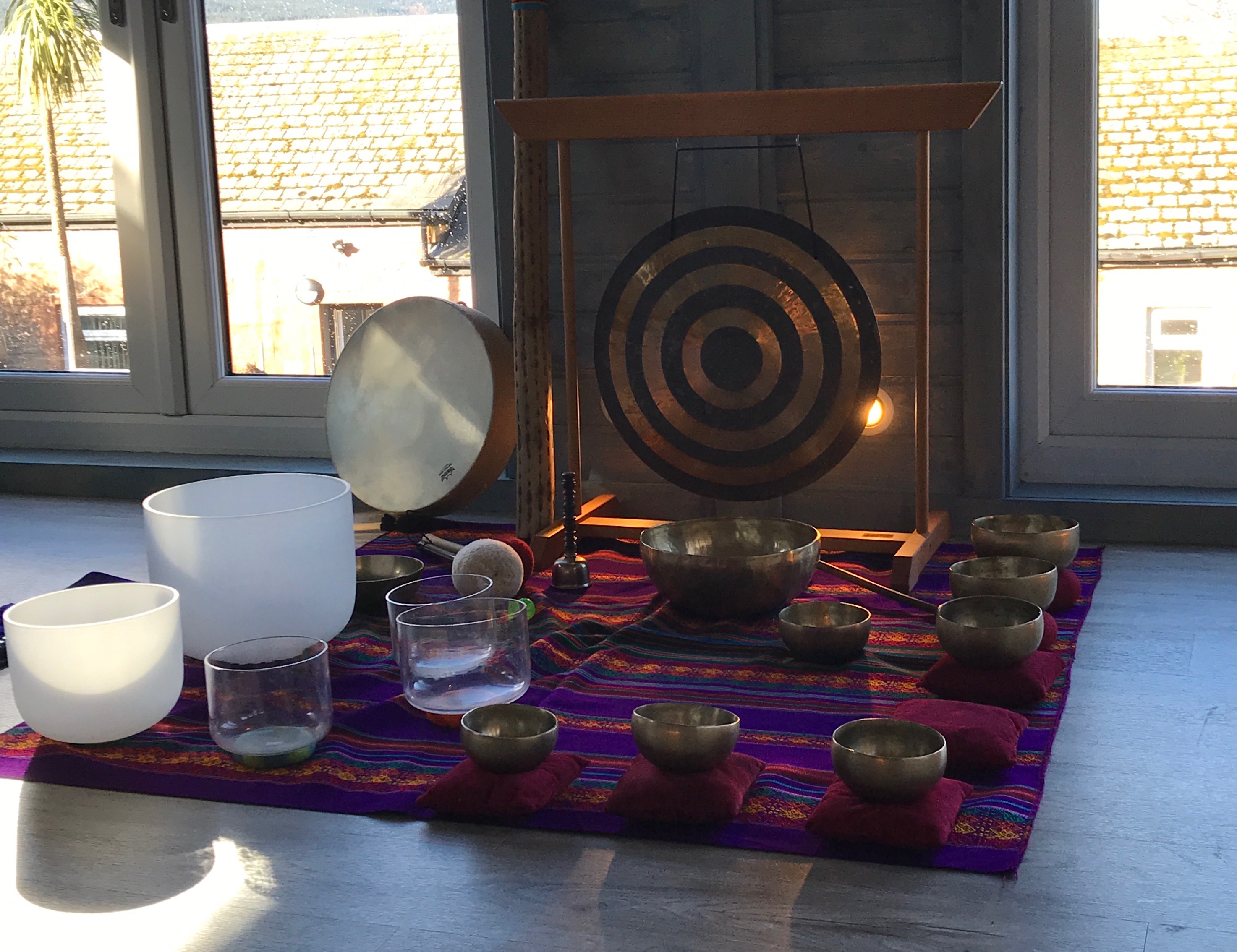 Bronze and glass cups and bowls laid out on a colourful mat.