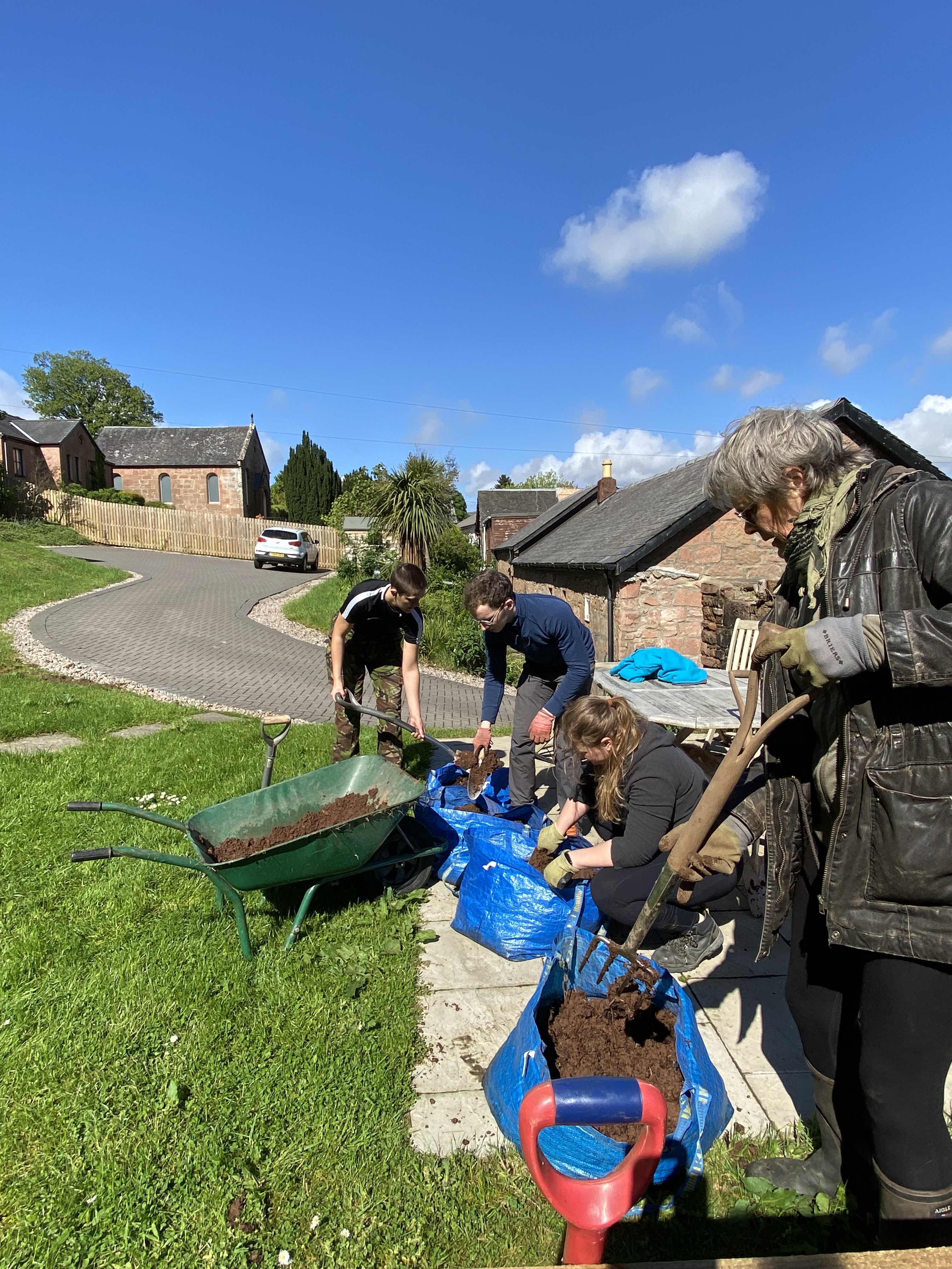 Some members of the group putting down soil outside on a sunny day.