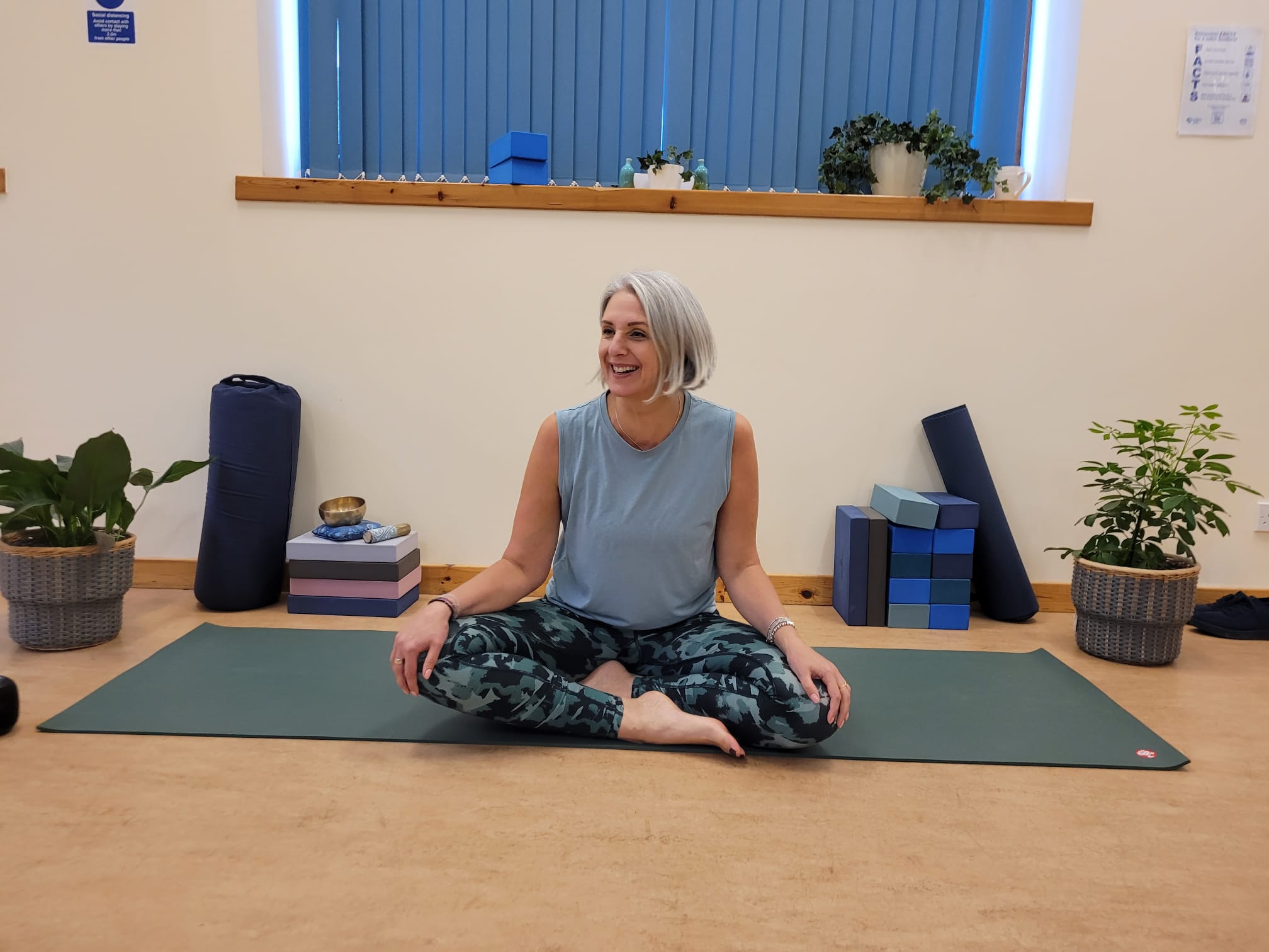 Person sitting on a yoga mat with legs crossed.