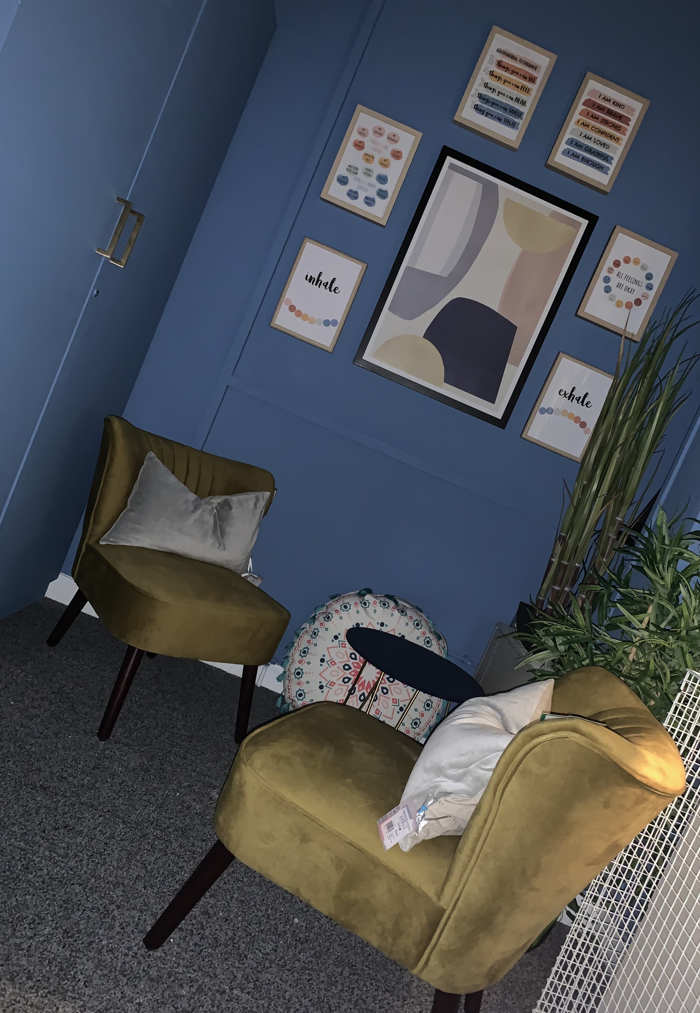 Blue room with pictures on the wall, two brown chairs and a table