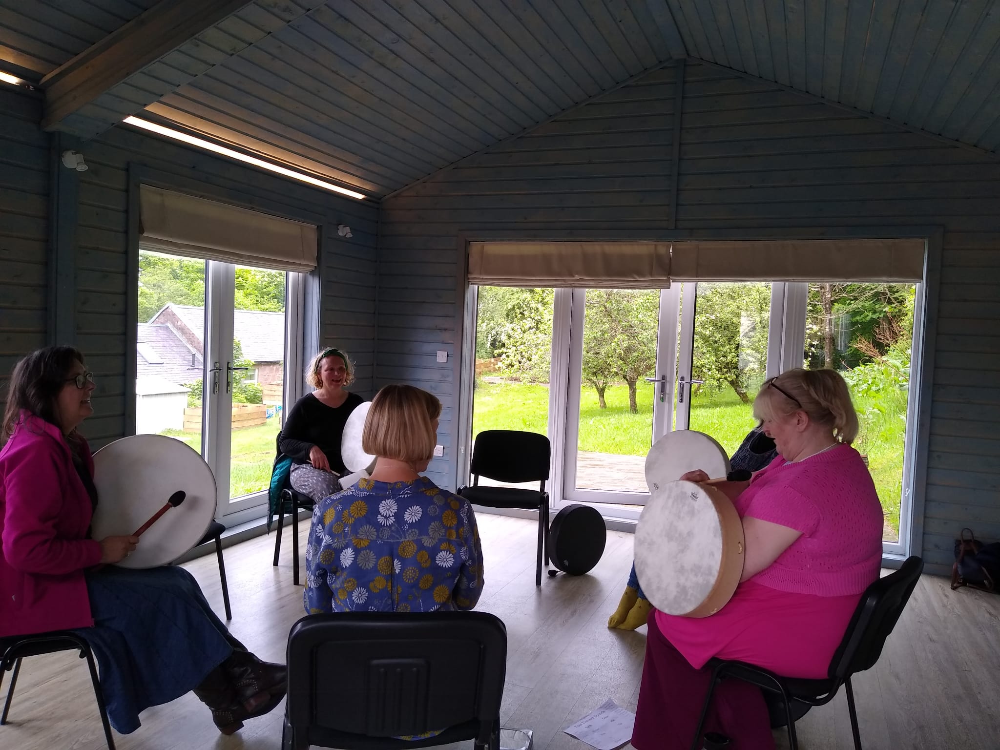 Women seated in a circle, drumming.